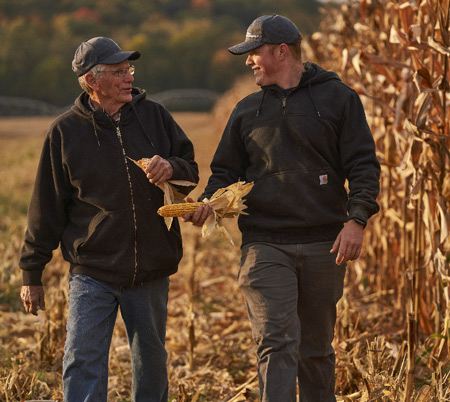 Multigenerational farmers walking next to crops image Multigenerational farmers walking next to crops image