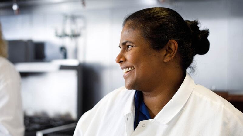 A woman food scientist smiles in a kitchen.
