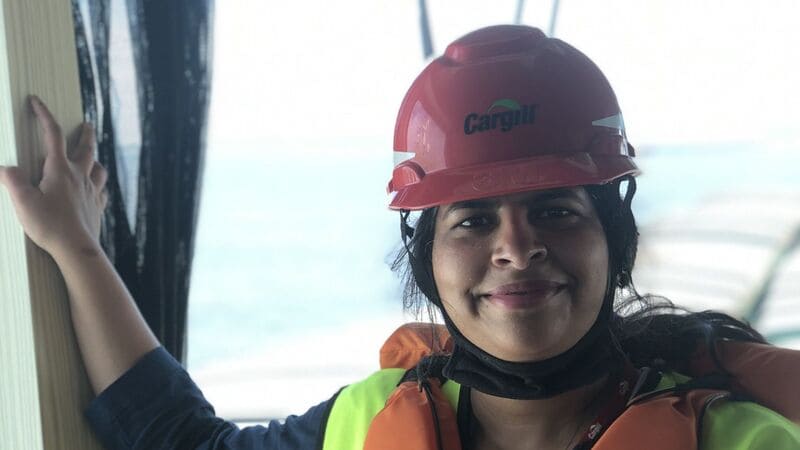 woman smiles while wearing a red hard hat with Cargill written on it.  woman smiles while wearing a red hard hat with Cargill written on it.
