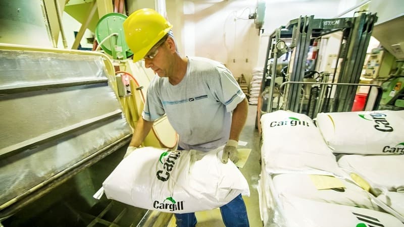 A farmer moves a bag of Cargill animal feed.  A farmer moves a bag of Cargill animal feed.