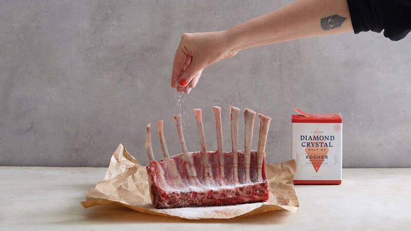 A person sprinkles Diamond Crystal Kosher Salt over a rack of ribs. A person sprinkles Diamond Crystal Kosher Salt over a rack of ribs.
