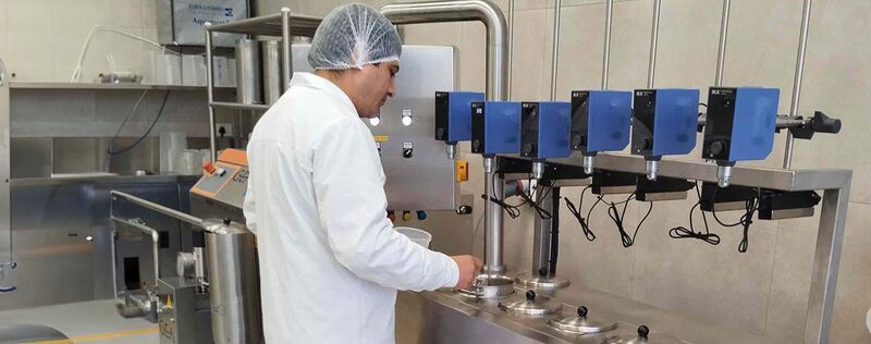 A food scientist in a white lab coat works with a machine in a lab.