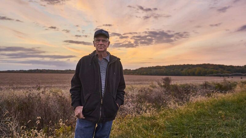A farmer stands in front of a field of corn and discusses the bioeconomy.