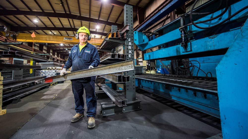 An employee holding a steel bar at a steel service center An employee holding a steel bar at a steel service center