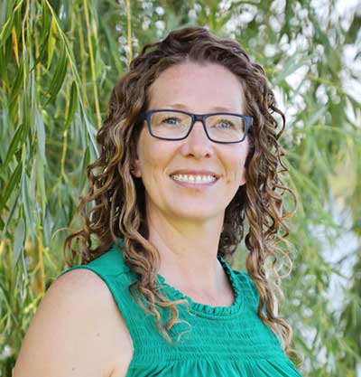conservation agronomist stands in front of rows of corn.  conservation agronomist stands in front of rows of corn.