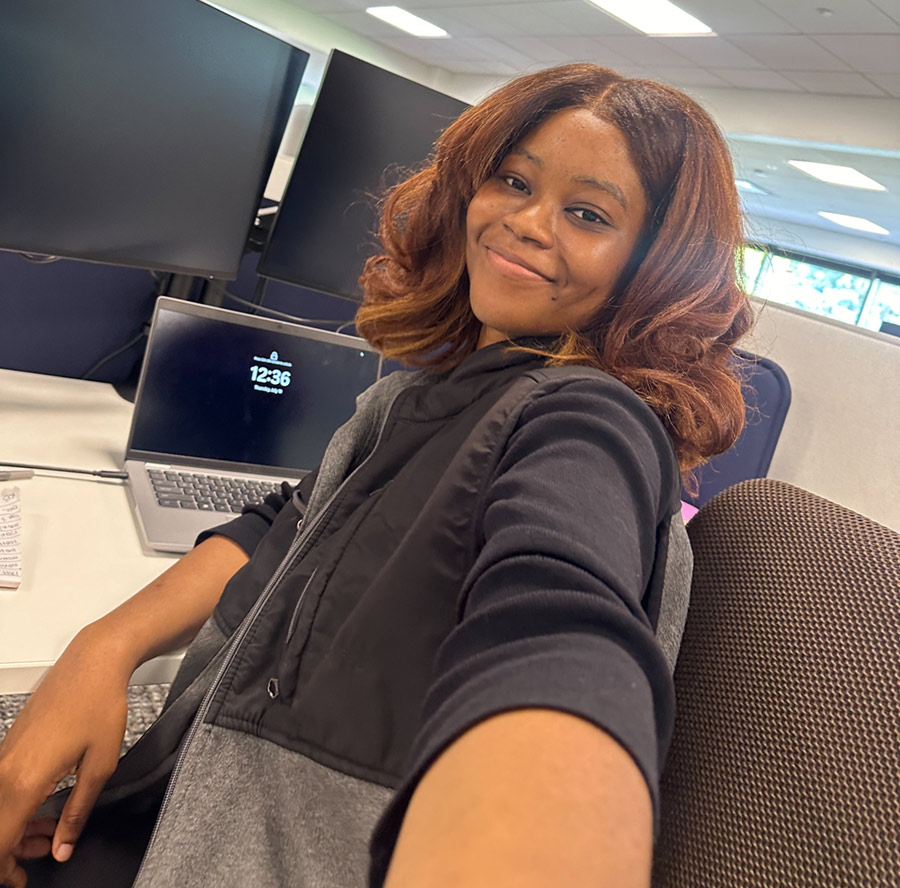 A young woman takes a selfie at a desk.