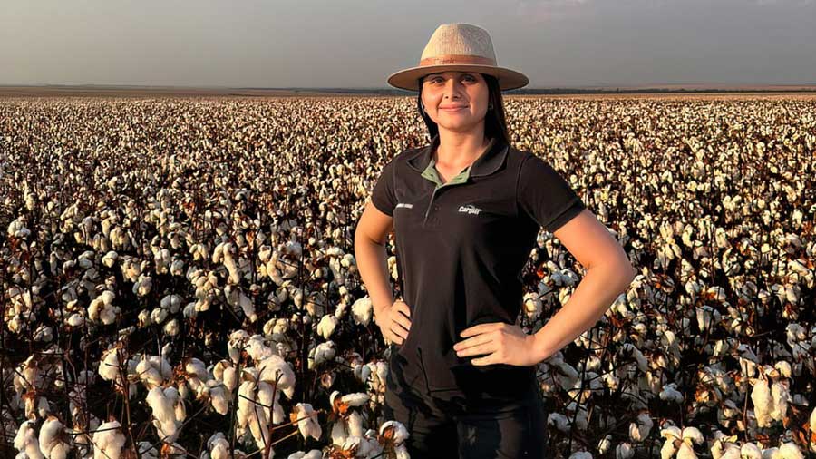 A woman wearing a black Cargill shirt stands in a field of cotton.  A woman wearing a black Cargill shirt stands in a field of cotton.