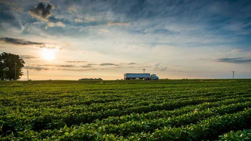 A truck drives on a highway near farmland.
