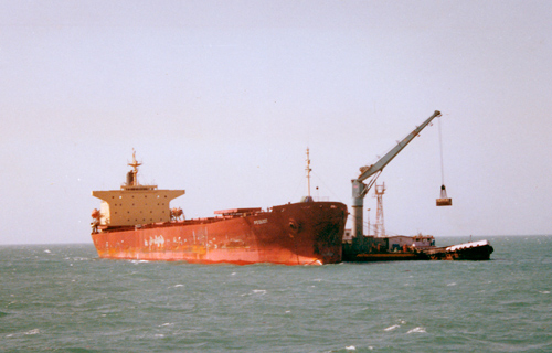 A ship unloads freight in the ocean waters outside India.