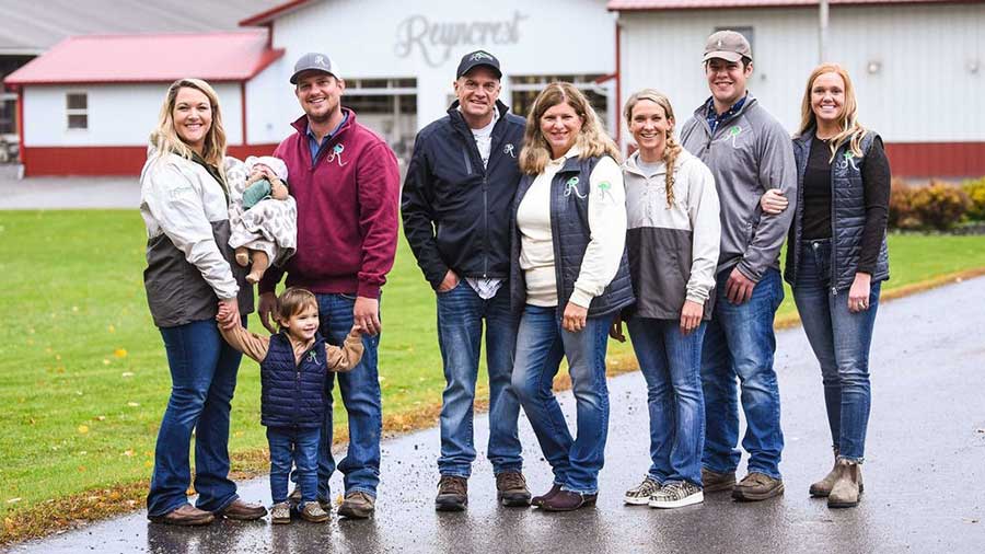 a family of nine people stand and smile outside a large building with Reyncrest written oni t.  a family of nine people stand and smile outside a large building with Reyncrest written oni t.