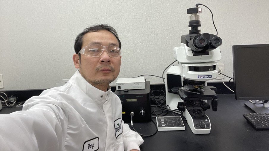 A Cargill crop innovation scientist sits in front of a light microscope.  