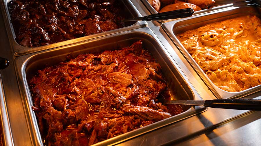 Three bins of chicken in a hot bar with large spoons in each.  Three bins of chicken in a hot bar with large spoons in each.