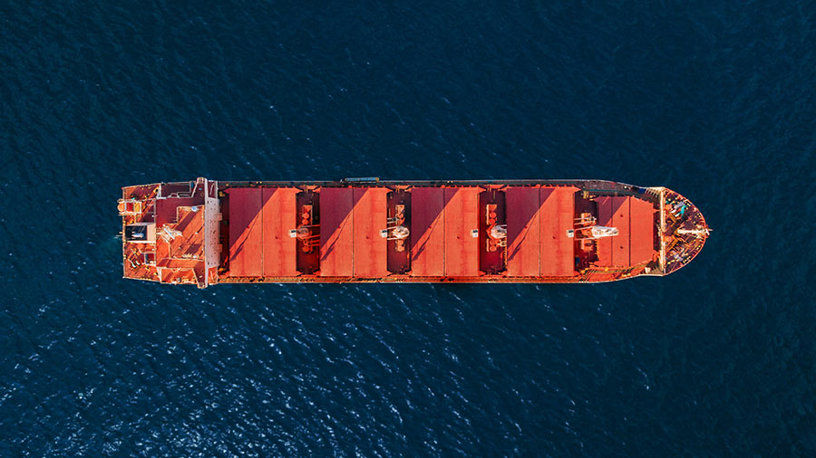 An overhead view of a large red container ship on the water.  An overhead view of a large red container ship on the water.