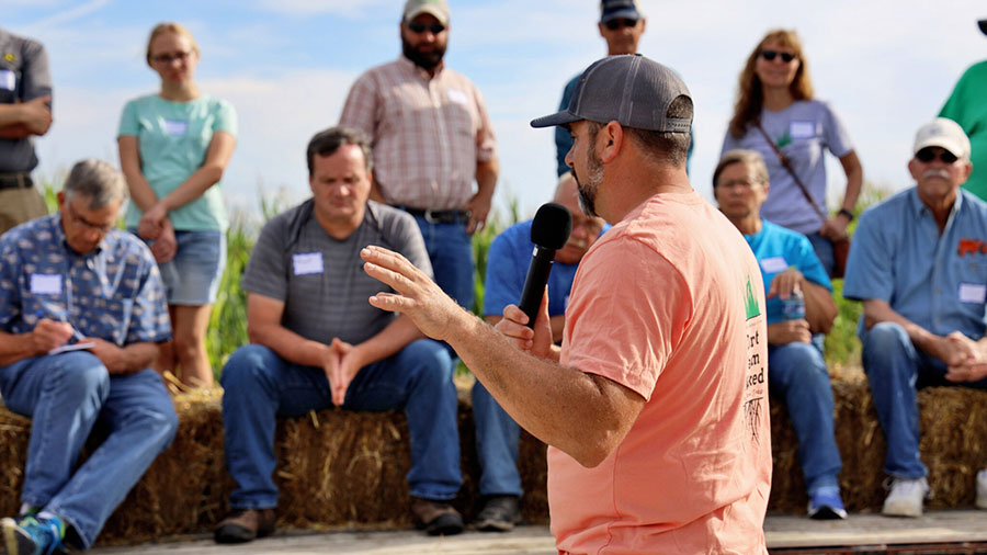 A man speaks into a microphone as he stands in front of a group of Iowa farmers.  A man speaks into a microphone as he stands in front of a group of Iowa farmers.
